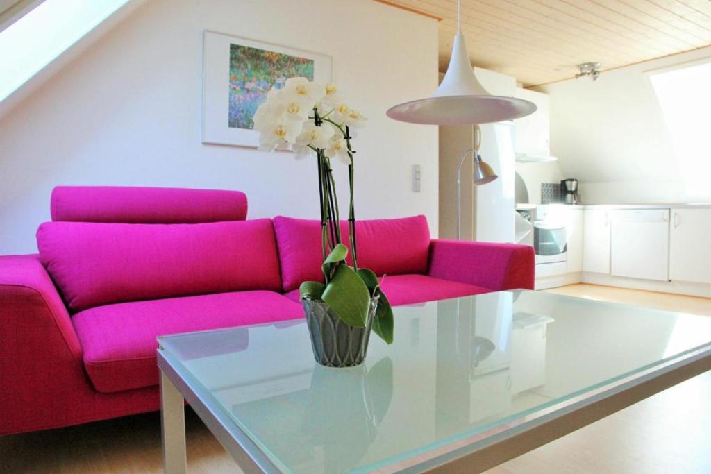 a living room with a pink couch and a glass table at Bornholm Majalis in Rønne