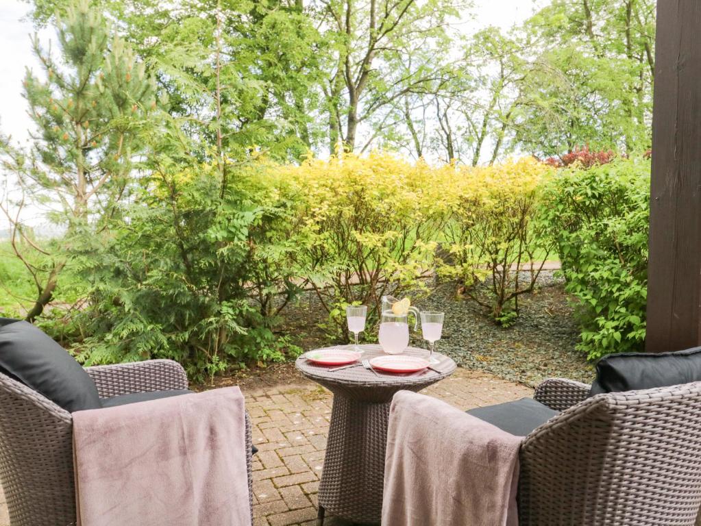 un patio con 2 sillas y una mesa con copas de vino en Cosy Corner in the Lakes en Penrith