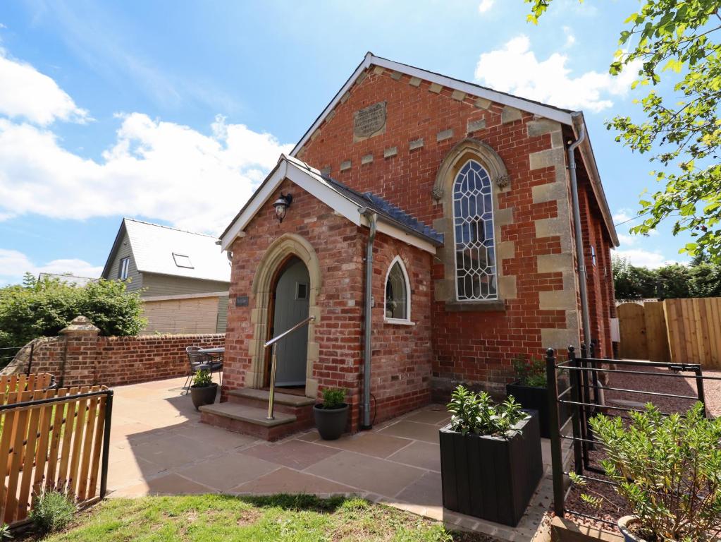 a small brick church with a fence at The Old Chapel in Hereford