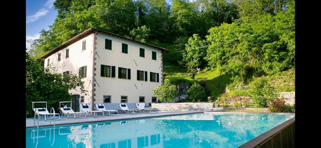 una gran piscina con sillas y un edificio en Monnalisa, en Castiglione di Garfagnana