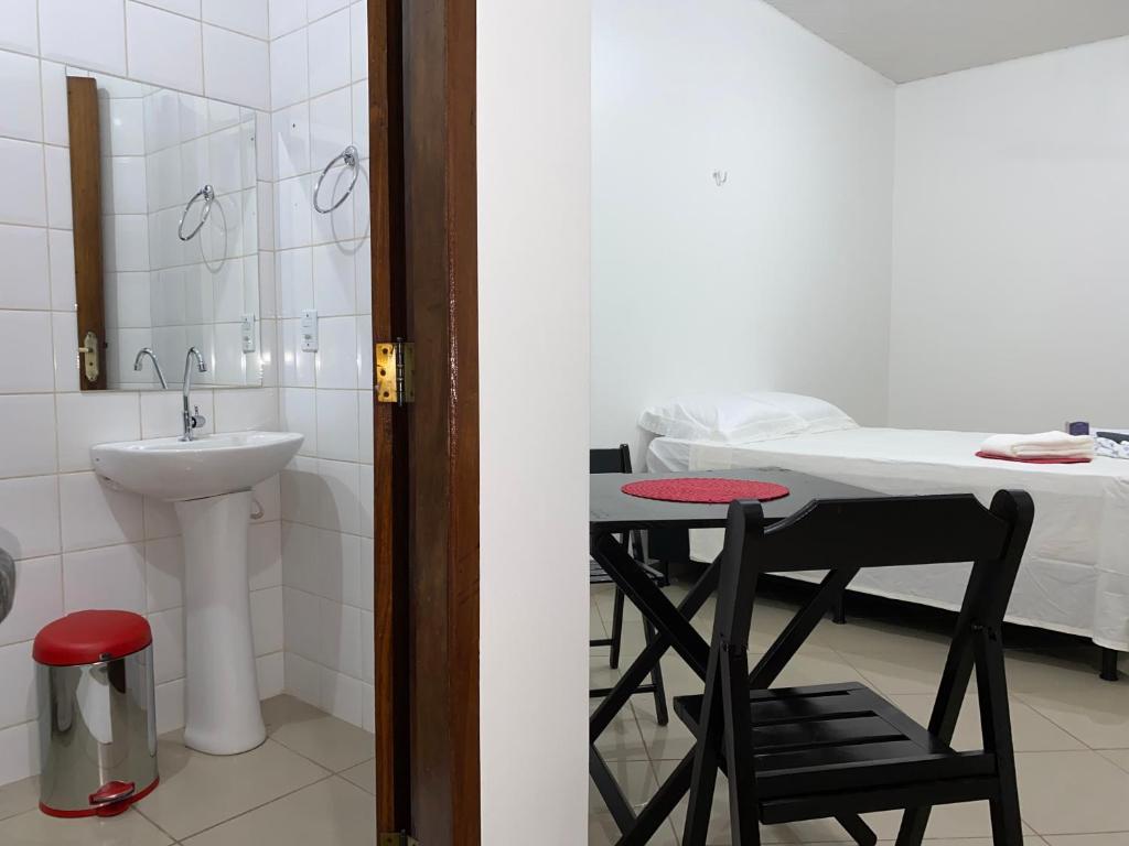 a bathroom with a sink and a table with a chair at Hotel SALINE PRAIA in Salinópolis