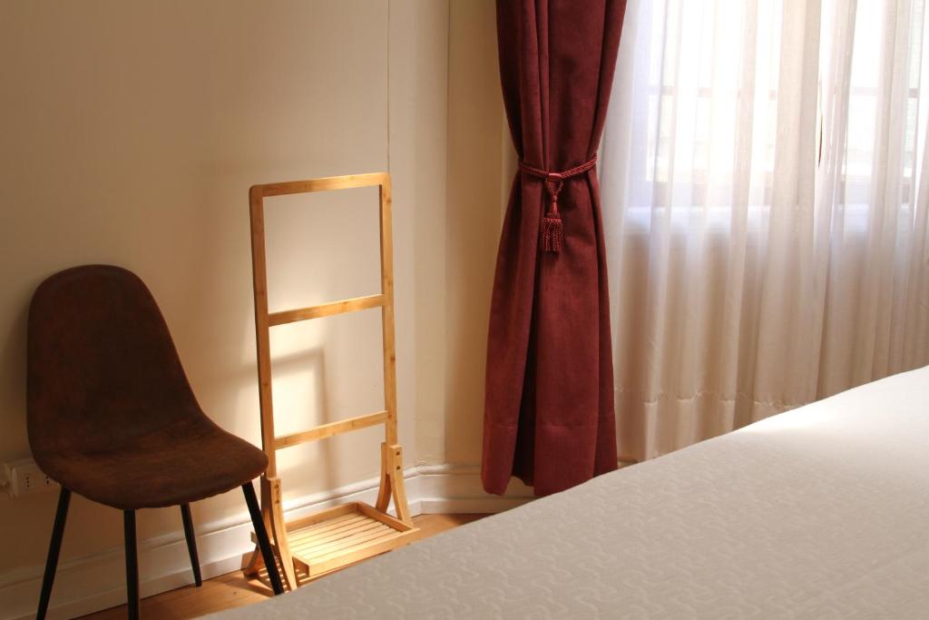 a bedroom with a bed and a chair next to a window at Hotel Boutique Casa Conde in Santiago