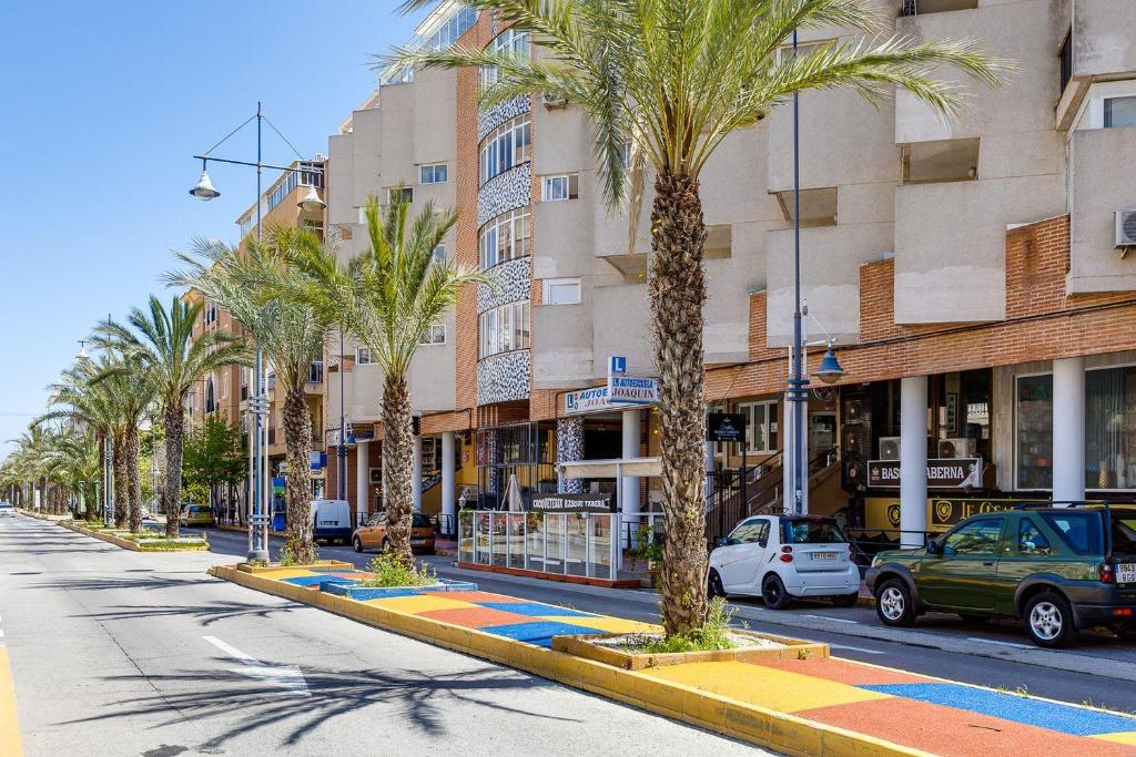uma rua com palmeiras em frente a um edifício em Studio Apartment Santana Habaneras - 18 at Beach with Garage, Pool and Lift em Torrevieja