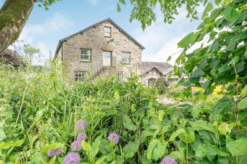 uma casa velha atrás de um campo de plantas em 5 The Granary em Burneside