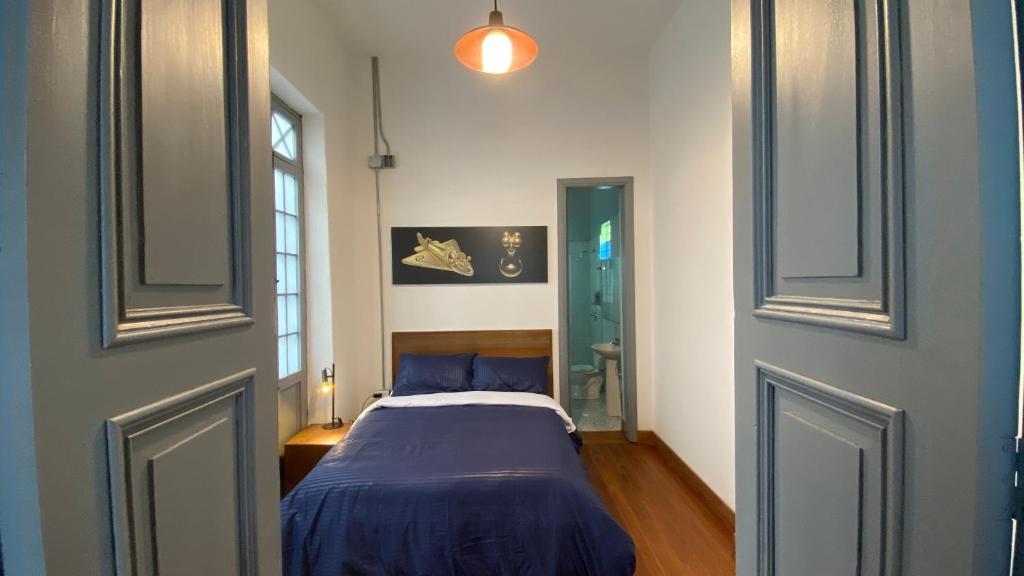 a bedroom with a bed with a blue comforter at REPUBLICANA CASA HOSTAL - HABITACION 1 QUIMBAYA in Bogotá