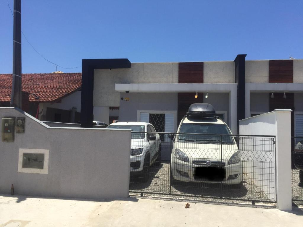 Casa Enseada, Prainha, Praia Grande prox mar في ساو فرانسيسكو دو سول: سيارتين متوقفتين في موقف للسيارات أمام منزل