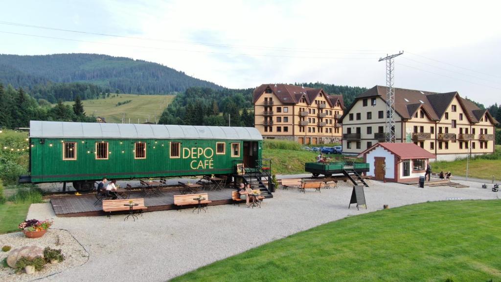 un patio de trenes con un vagón de tren verde en una ciudad en Apartmány Ski Telgárt, en Telgárt