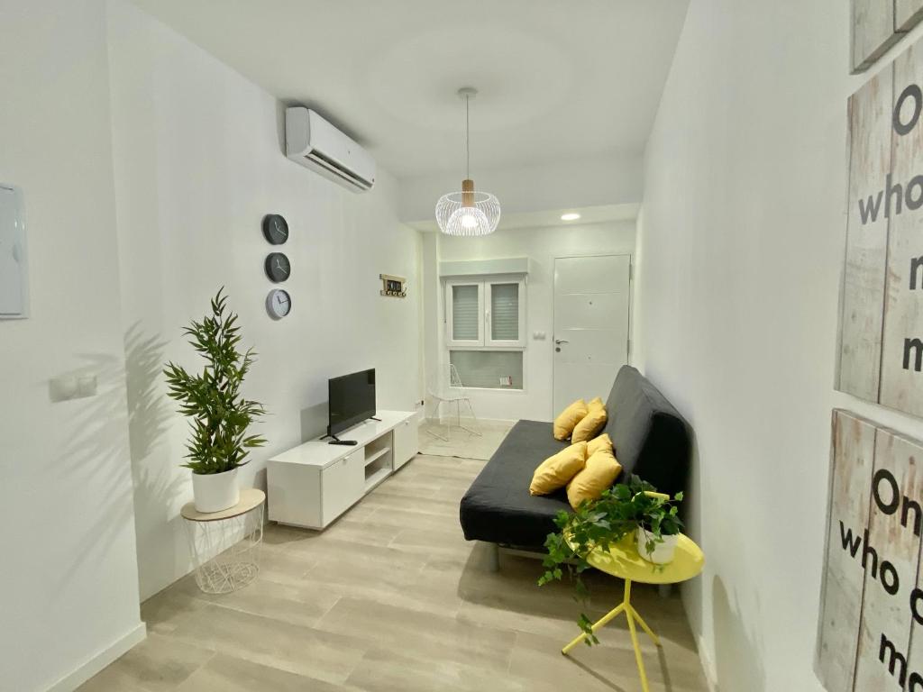 sala de estar con sofá negro y TV en Mejorana Apartament, en Madrid