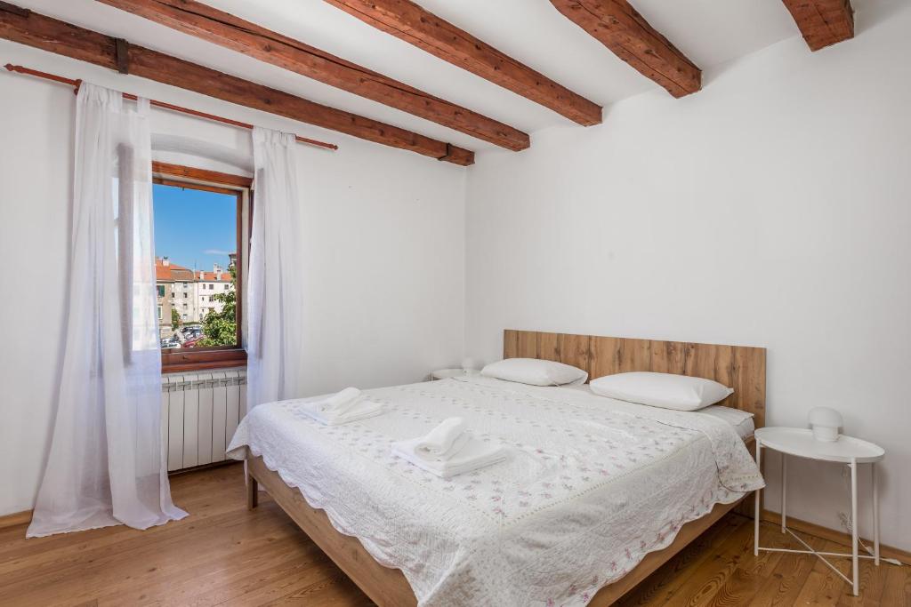 ein weißes Schlafzimmer mit einem Bett und einem Fenster in der Unterkunft Apartment Lucci in Rijeka