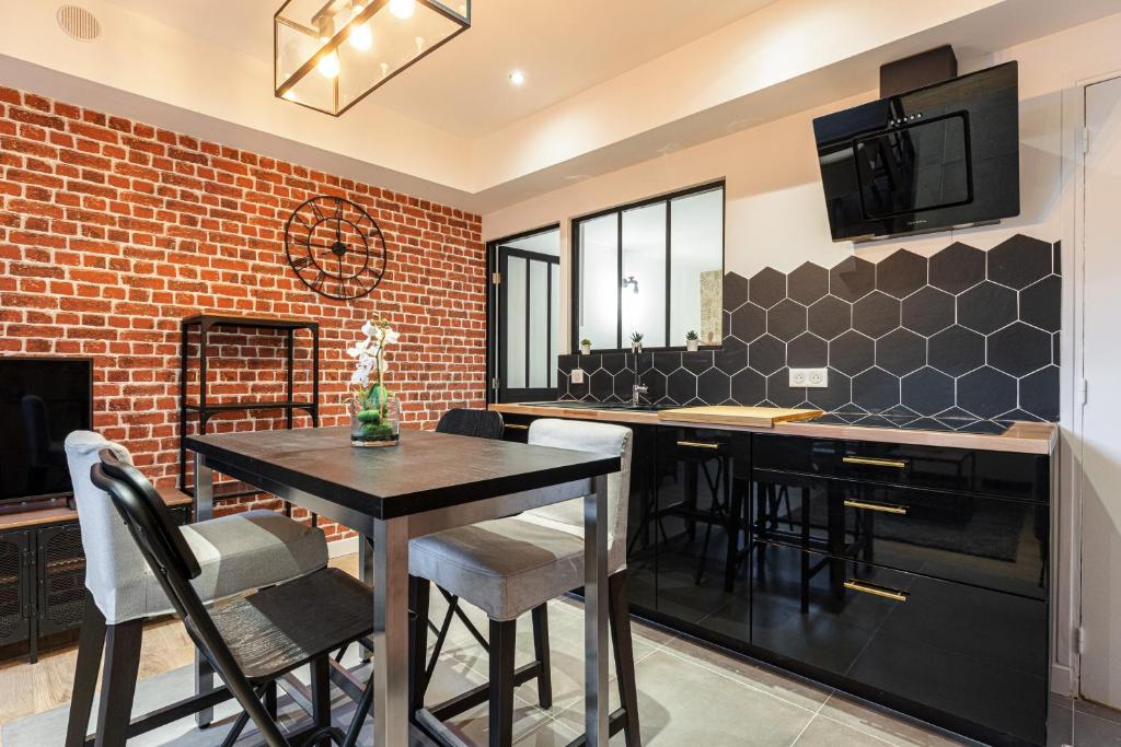 a kitchen with a black table and chairs and a brick wall at LOFT 1 CHAMBRE PRES MER in Nice