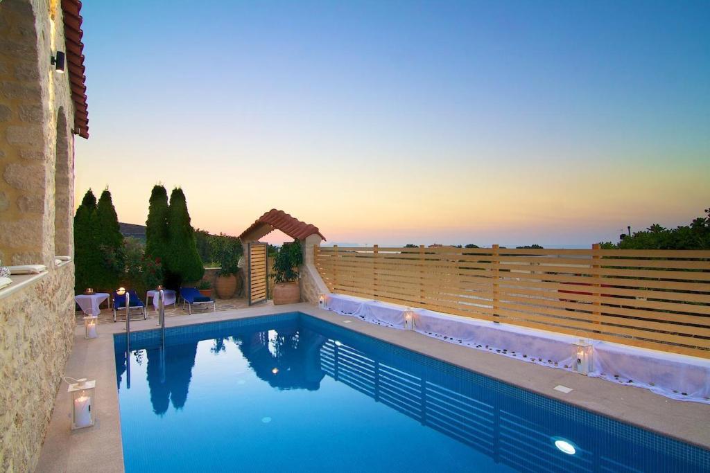 a swimming pool in front of a house with a sunset at Elena Villa, an Authentic Retreat with Private Pool, By ThinkVilla in Roussospítion