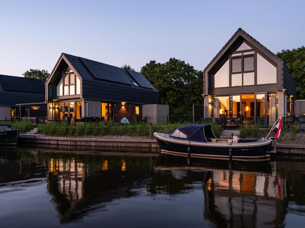 a house with a boat sitting in the water at Villa in Balk with Private Jetty on Slotermeer in Balk