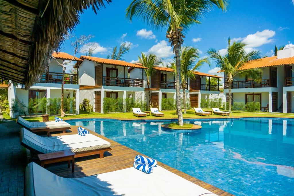 een resort met een zwembad en palmbomen bij Villa Zen Hotel in Camocim