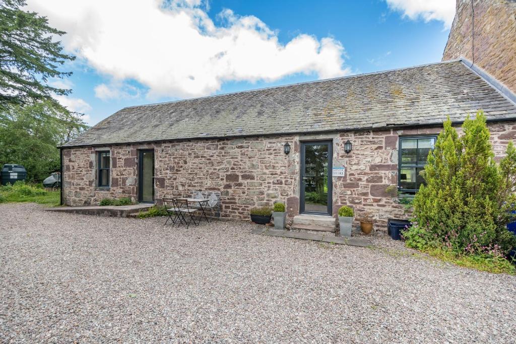 um antigo chalé de pedra com uma entrada de cascalho em The Garden Cottage em Doune