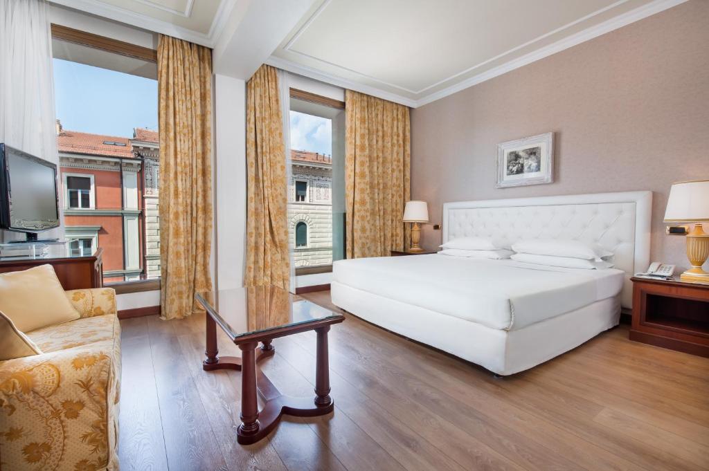 a large bedroom with a white bed and a couch at Hotel Internazionale in Bologna