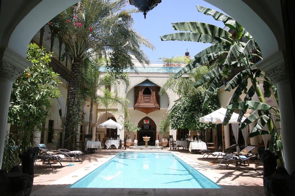 a large swimming pool in a building with palm trees at Demeures d'Orient Riad & Spa in Marrakesh
