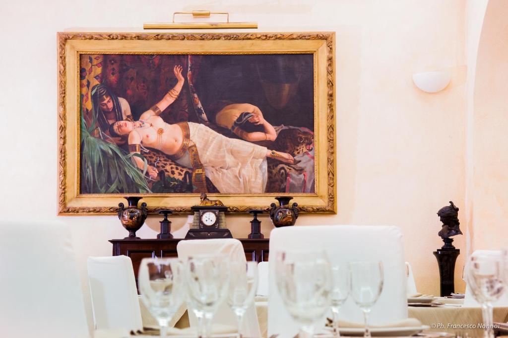 ein Gemälde an der Wand über einem Tisch mit Brille in der Unterkunft Hotel Flora in Cagliari