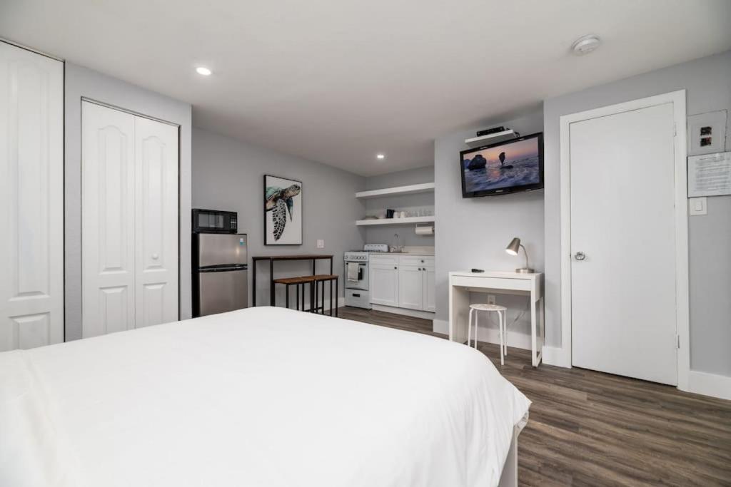 a bedroom with a white bed and a kitchen at Shell on the Beach 107 - RENOVATED in Hollywood