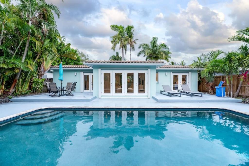 a swimming pool in front of a house with palm trees at Luxurious Fort Lauderdale Pool Home in Fort Lauderdale