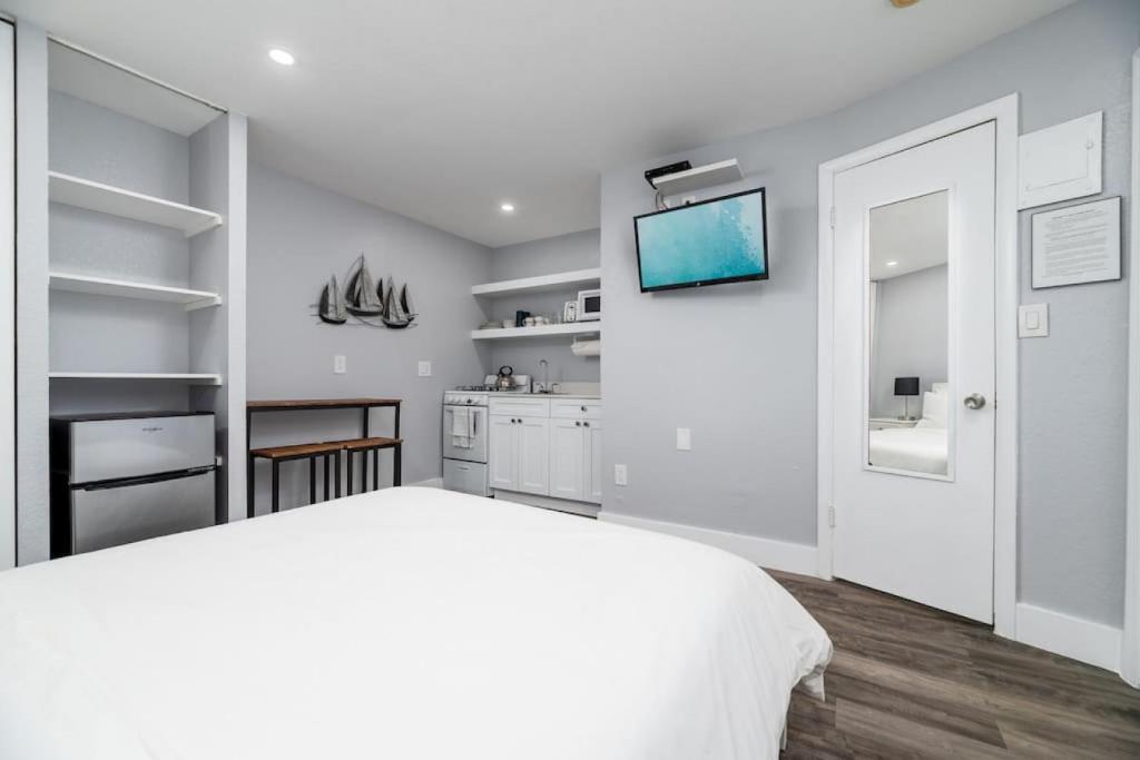 a white bedroom with a white bed and a tv at Shell on the Beach 103 - RENOVATED in Hollywood