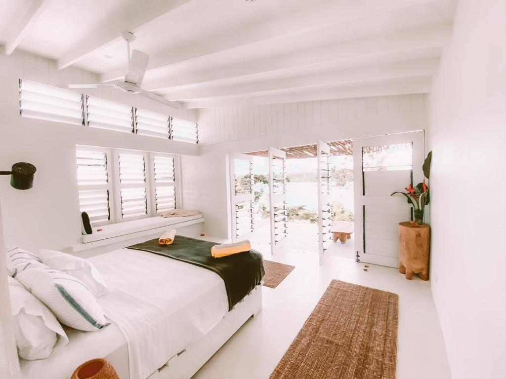 a white bedroom with a large bed and windows at The Moso in Port Vila