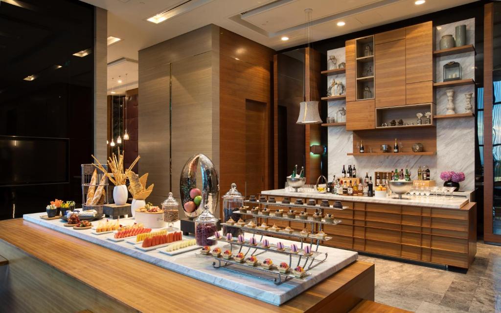 A polished buffet display with pastries, desserts, fruit and a fully stocked drinks counter.