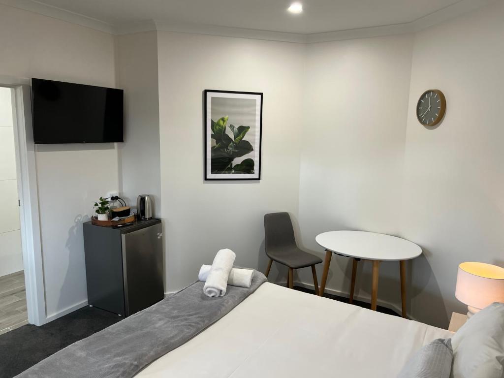 sypialnia z łóżkiem, stołem i zegarem w obiekcie BENDIGO BOTANIC MOTEL- with KING BEDS-REFURBISHED 2022 w mieście Bendigo