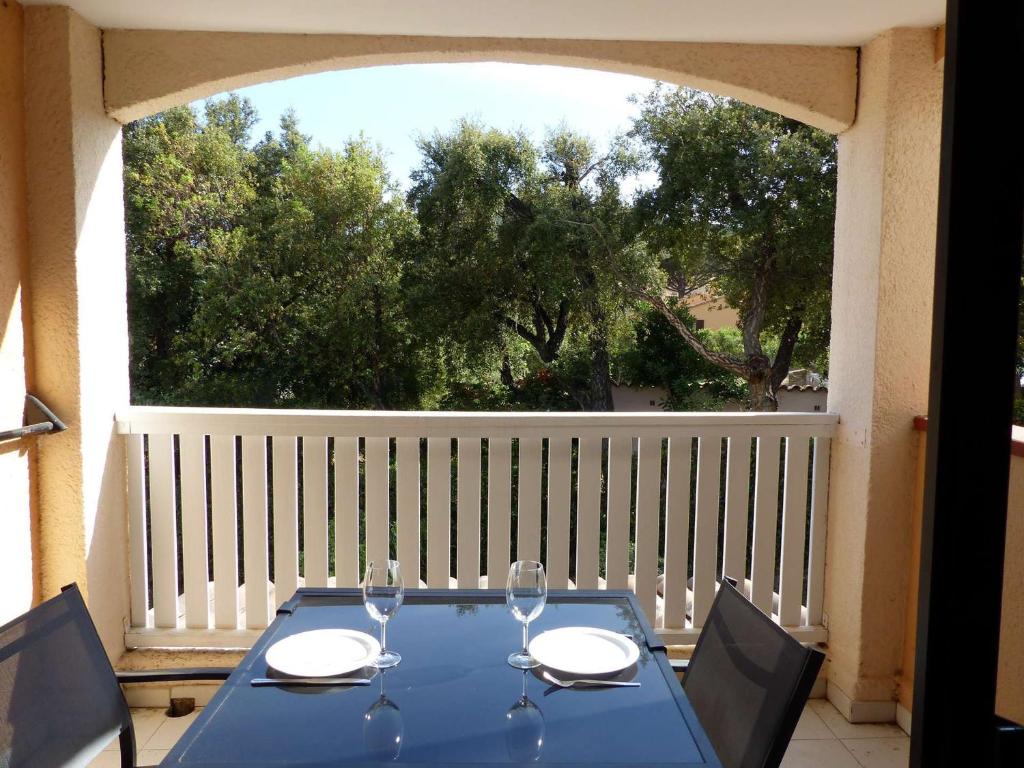 una mesa azul con copas de vino en el balcón en Studio Le Lavandou, 1 pièce, 4 personnes - FR-1-308-152, en Le Lavandou