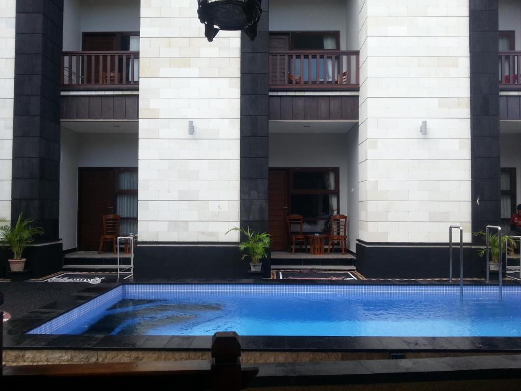 a swimming pool in front of a building at New ASTA GRAHA GUESTHOUSE in Jimbaran