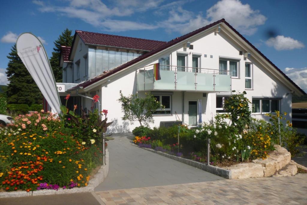 una casa blanca con flores delante en Landpension Wachtkopf Ferienwohnungen, en Vaihingen an der Enz