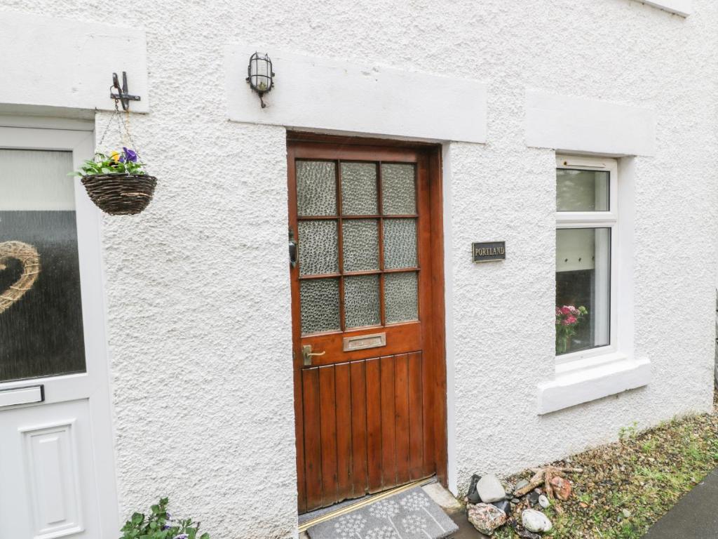 a white house with a wooden door and a window at Portland in Brodick