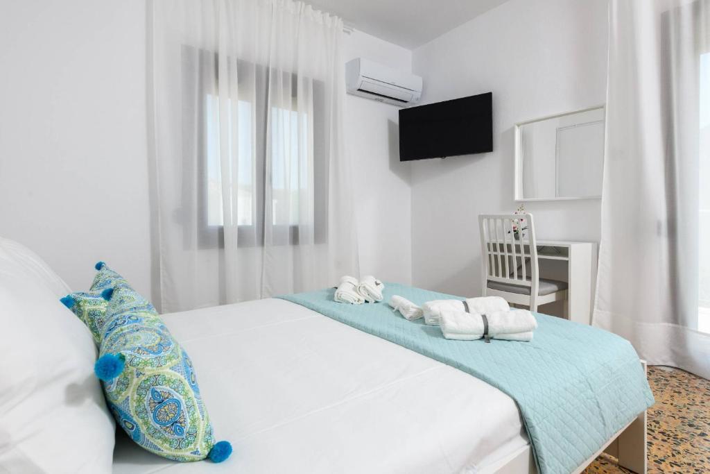 Un dormitorio blanco con una cama con toallas. en Whitegold Apartments Panagia en Panagia