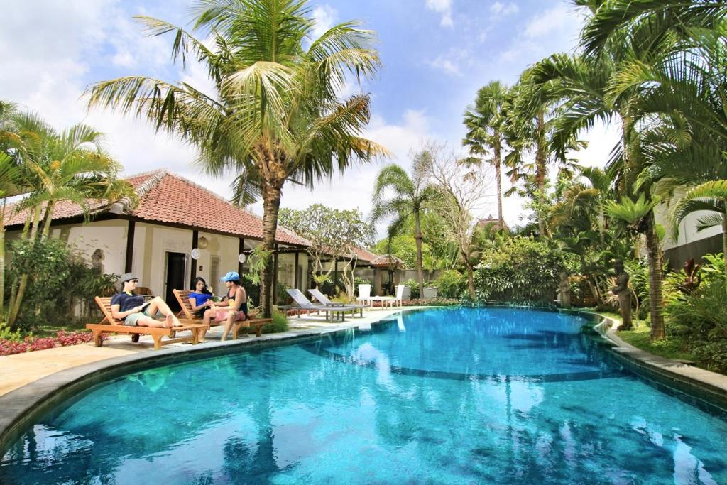 people sitting in chairs by a swimming pool in a villa at The Radian Villa in Canggu