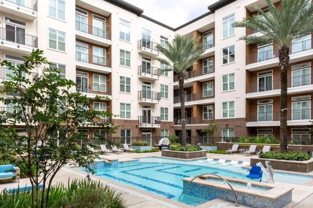 an apartment building with a swimming pool and palm trees at Luxury Apartment Close to Everything w Free Parking 5 in Houston