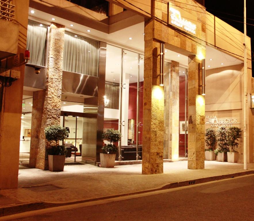 De Los Arroyos Apart Hotel في سان نيكولاس دي لوس أرويوس: مبنى يوجد أمامه نباتات الفخار في الليل