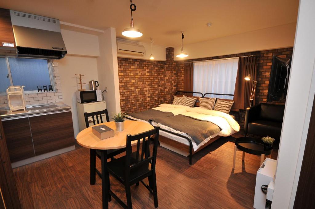 een slaapkamer met een bed en een tafel en een keuken bij Maison Milano Nakatsu Apartment in Osaka