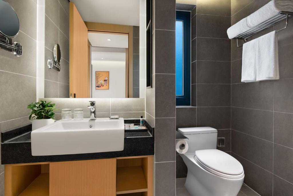 a bathroom with a sink and a toilet and a mirror at Citadines Gaoxin Chengdu in Chengdu