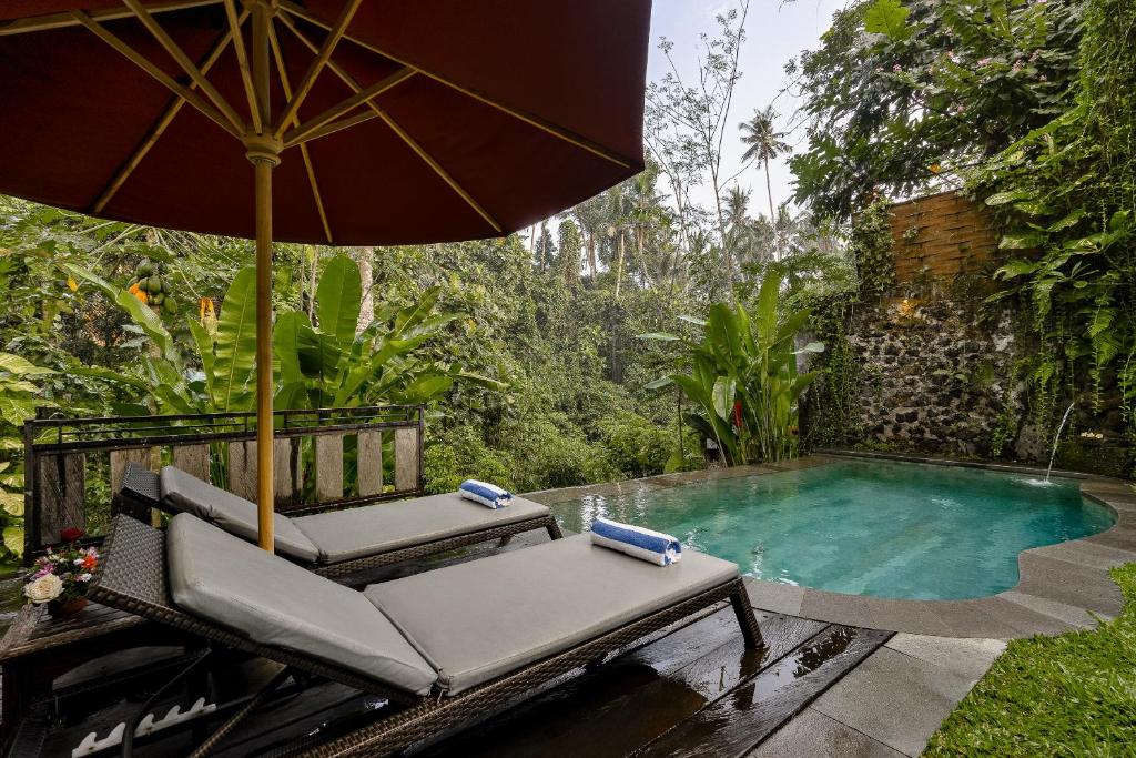 einen Stuhl und einen Regenschirm neben einem Pool in der Unterkunft Bubu Mesari Ubud Villa in Ubud