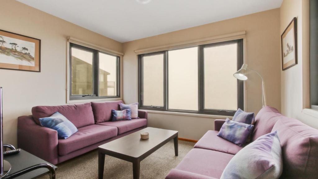 a living room with purple couches and windows at Snowtel 1 in Mount Hotham