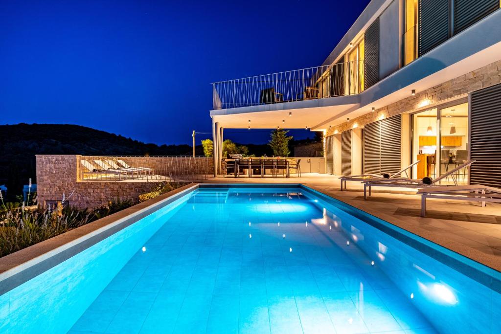 een zwembad voor een huis 's nachts bij Villa Mezano Žman in Žman