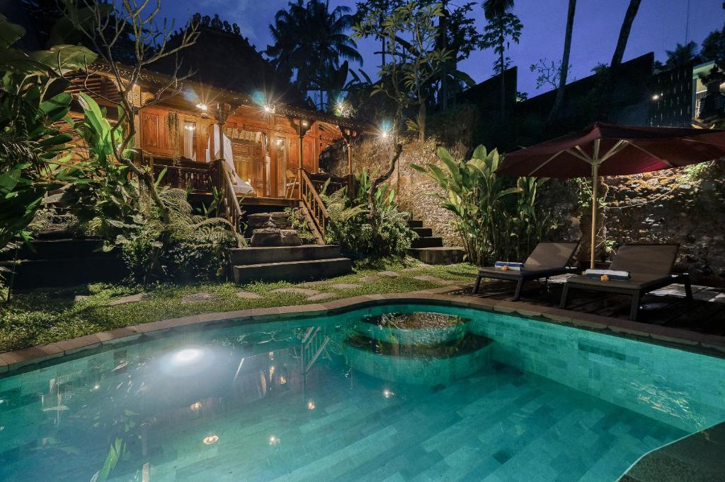 a swimming pool in front of a house at night at Bubu Mesari Ubud Villa in Ubud