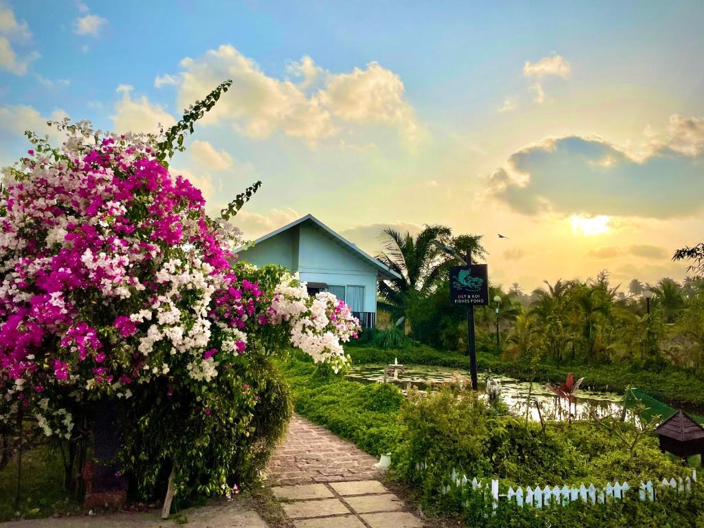 un jardin avec des fleurs roses et blanches devant une maison dans l'établissement Exotica Beach Retreats Diveagar, à Diveagar