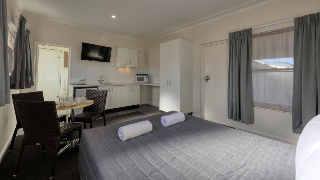 a bedroom with a bed and a table and a kitchen at Cowra Motor Inn in Cowra