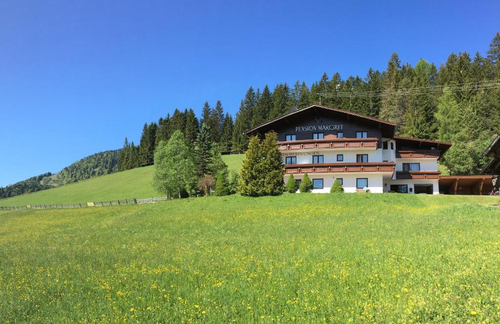 ein Haus auf einem Hügel mit einem grünen Feld in der Unterkunft Pension Margret in Leutasch