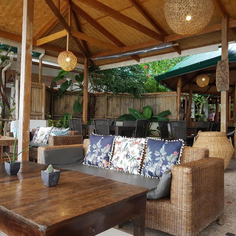 an outdoor patio with a wooden table and chairs at Golden Monkey Beach Hotel in El Nido