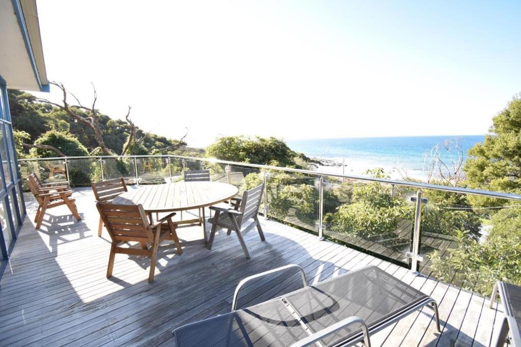 a deck with a table and chairs and the ocean at Wamoon Views Waratah Bay in Walkerville