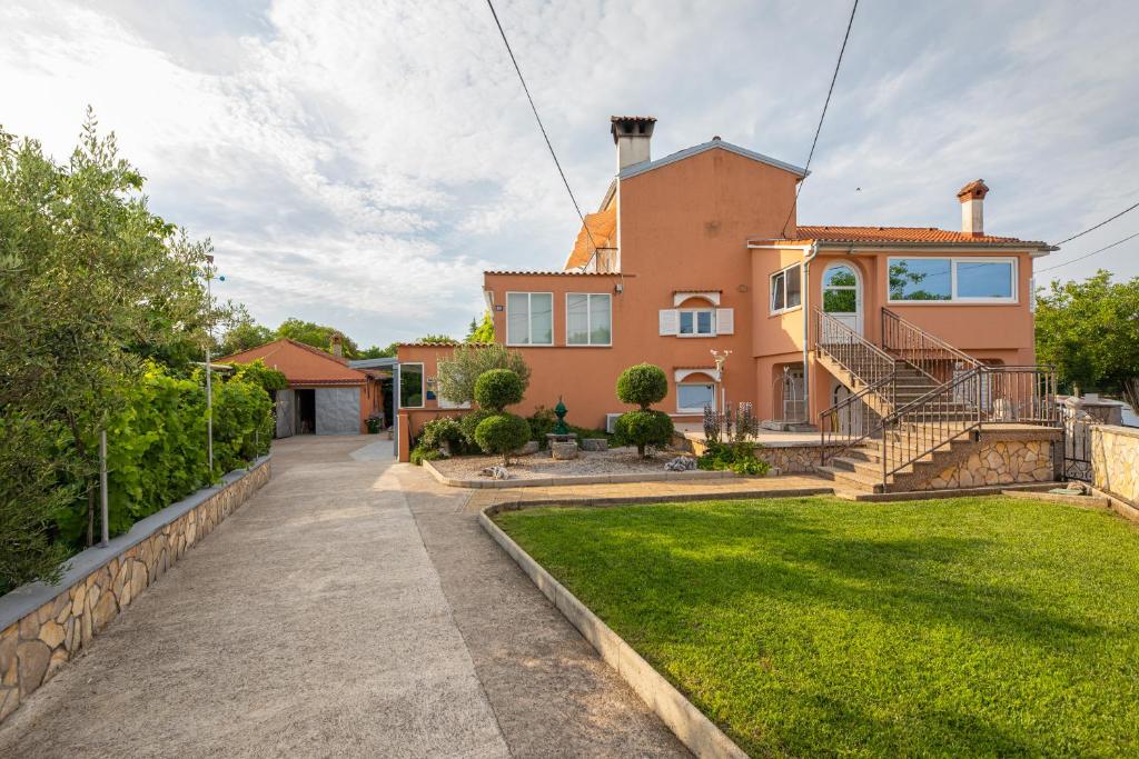 ein großes orangefarbenes Haus mit einem Rasenhof in der Unterkunft Apartment Josip Brusic in Gabonjin