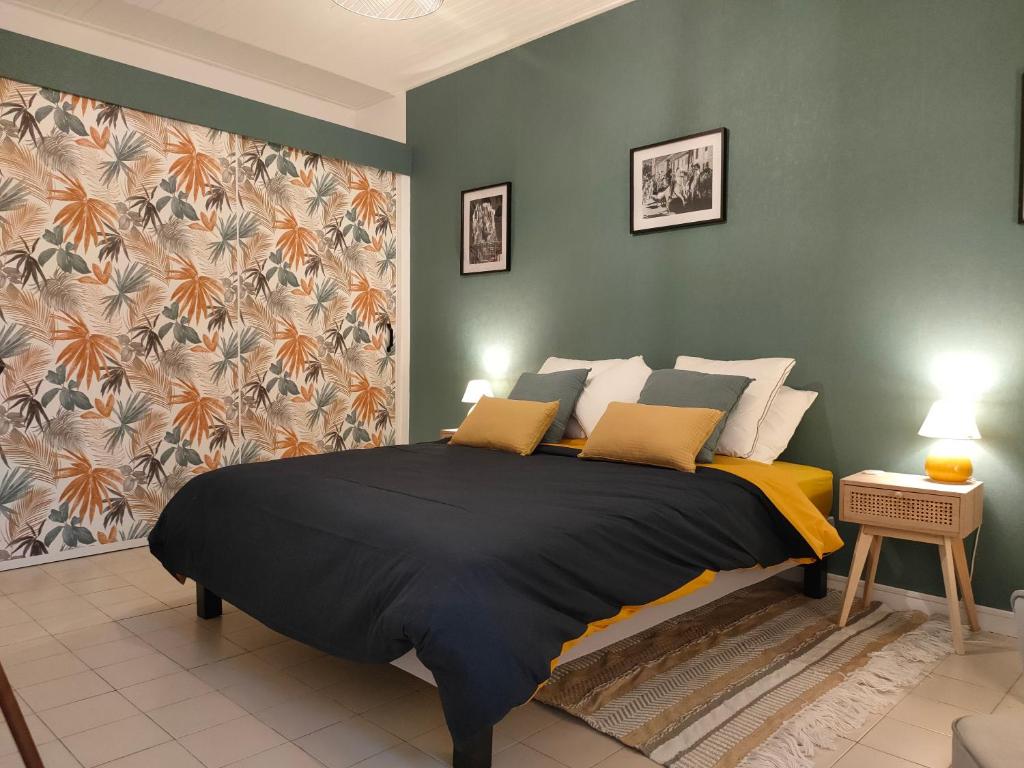 a bedroom with a large black bed with yellow pillows at La petite Arlésienne - Charmante maison de ville in Arles