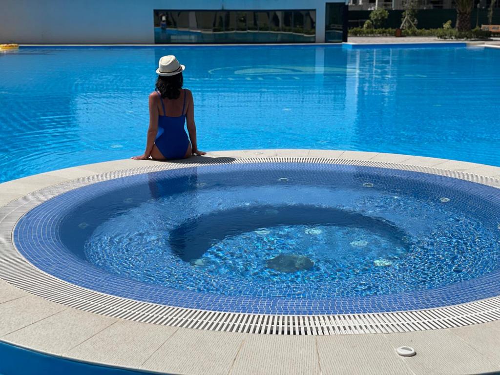 巴統的住宿－White Sails Residential Hotel，坐在大型游泳池旁的女人