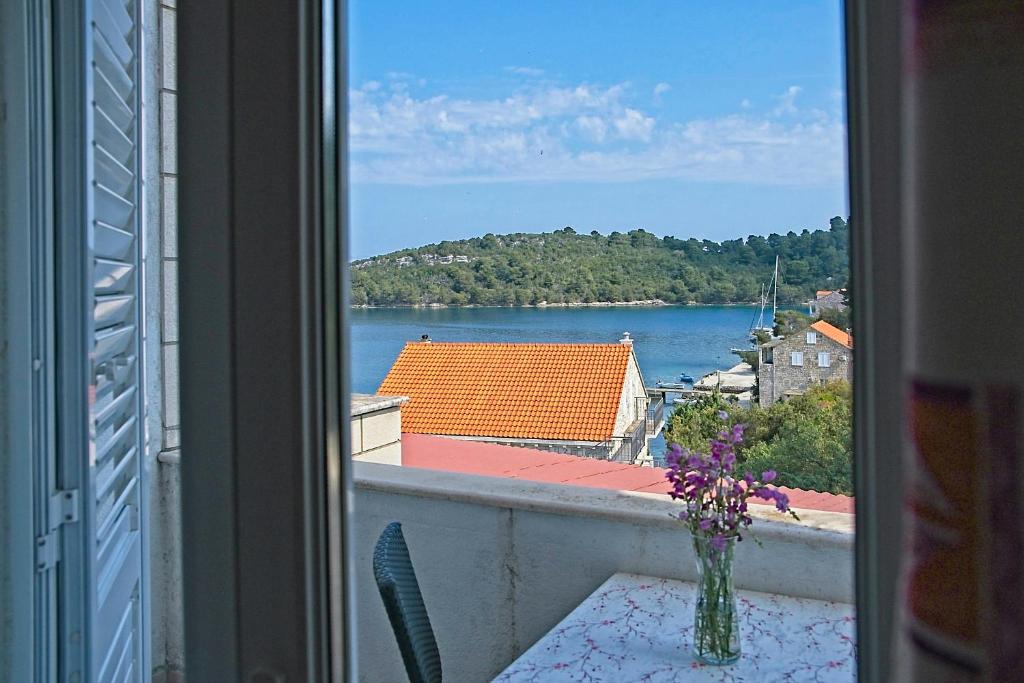 einen Balkon mit Blick auf das Wasser und einer Blumenvase in der Unterkunft Guest House Matana Pomena in Pomena